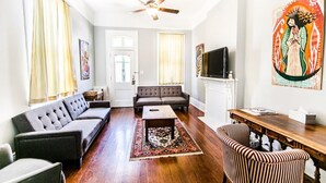 A living room with a sofa, armchairs, a coffee table, a television, and a fireplace.