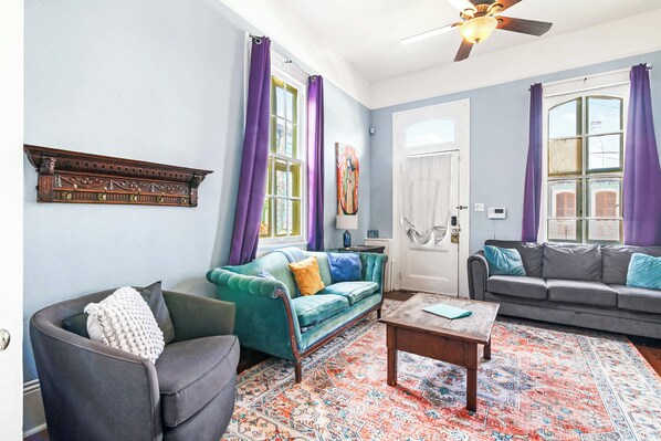 A living room with a green sofa, a grey sofa, a wooden coffee table, and a patterned rug.
