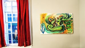 A room with a window, red curtains, and a painting on the wall.