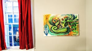 A room with a window, red curtains, and a painting on the wall.