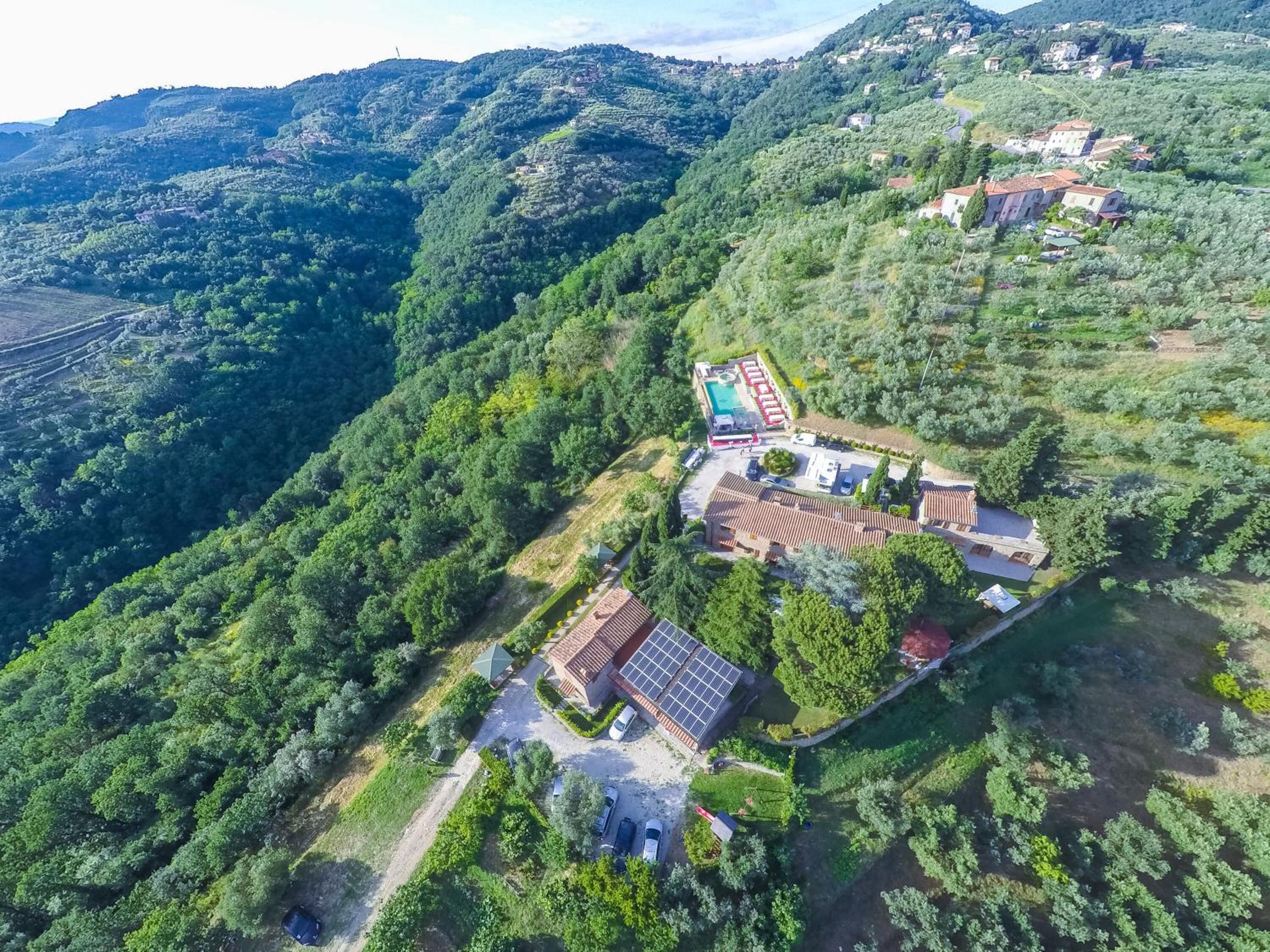 Una propiedad en una colina con piscina, paneles solares y un pequeño edificio.