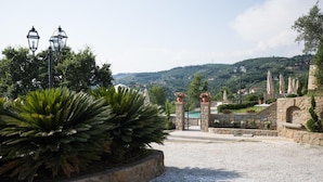 A gravel pathway leading to a pool area with stone walls and potted plants. - Borgo dei Gigli (Lamporecchio)