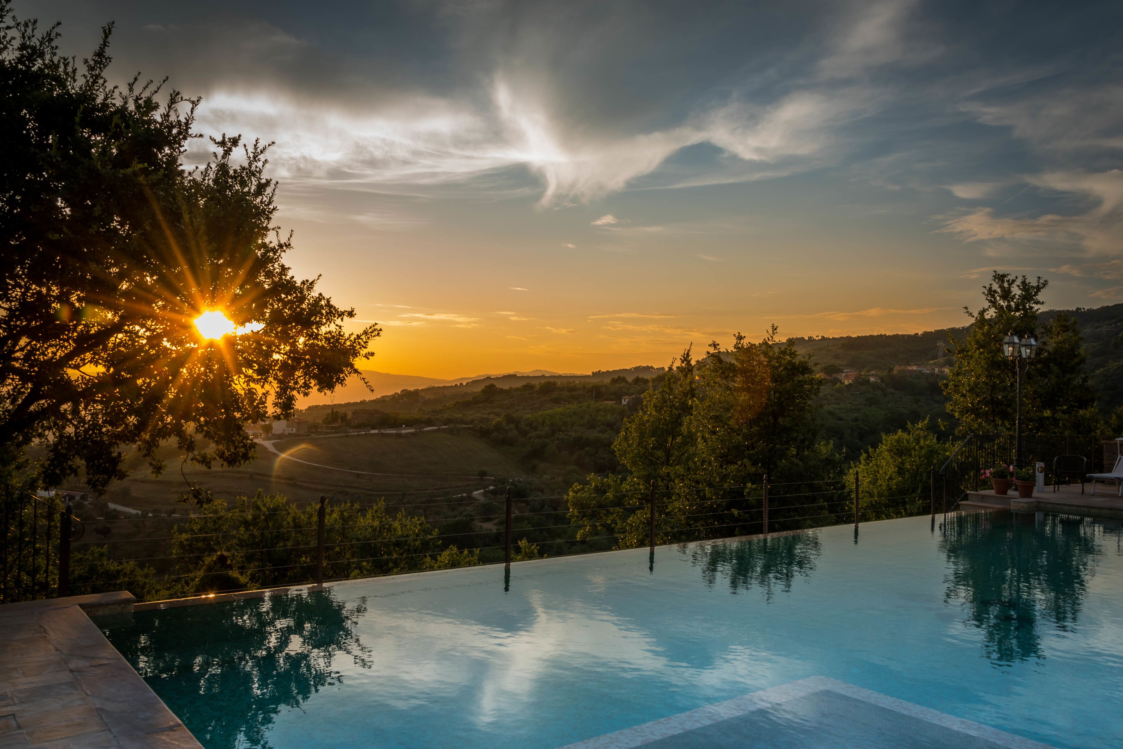 Una piscina con vistas a la puesta de sol sobre colinas ondulantes.