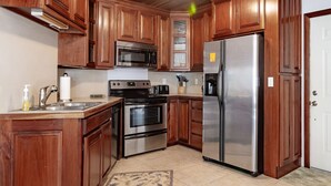 Une cuisine avec des meubles en bois, des appareils électroménagers en acier inoxydable et un sol carrelé.