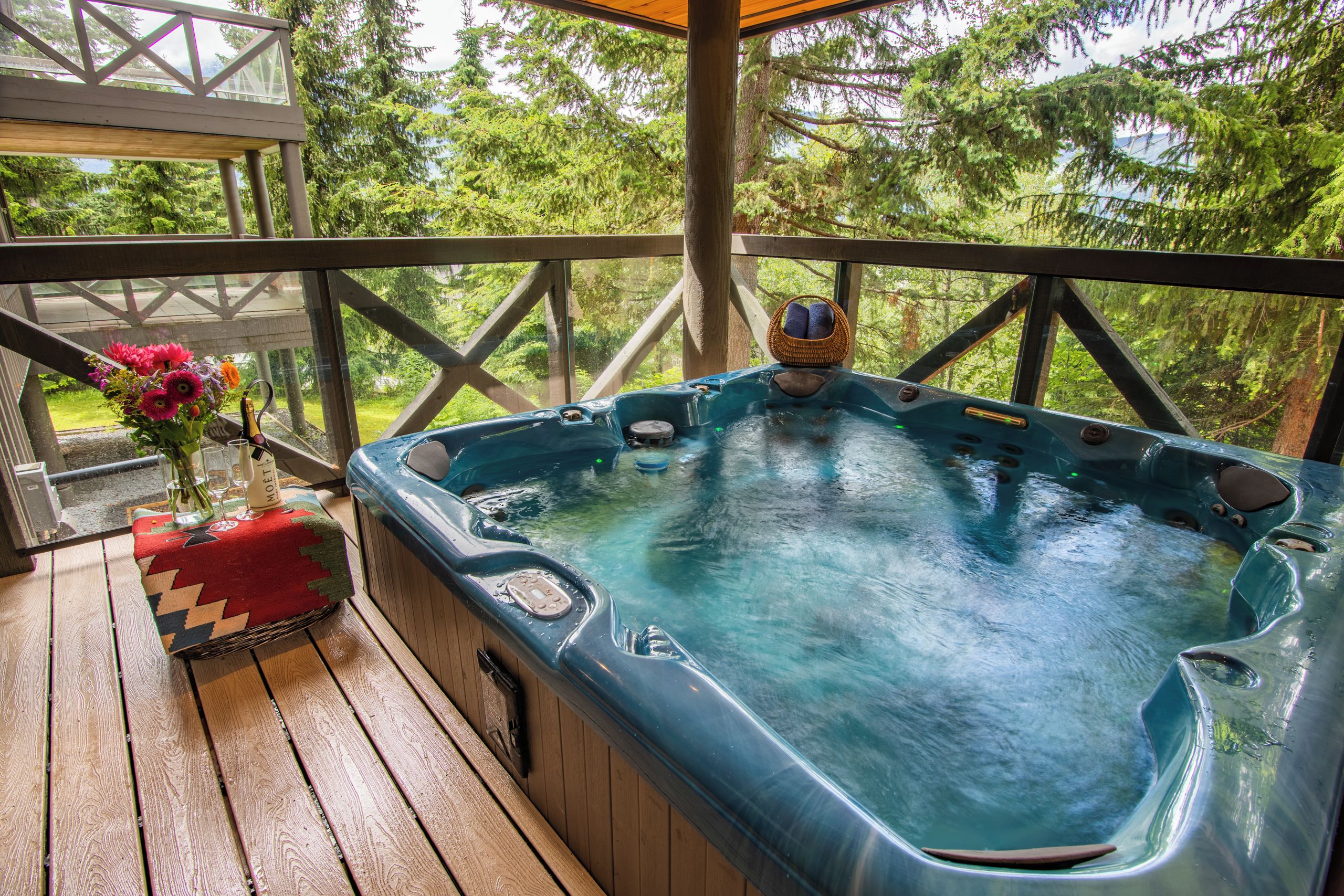 A hot tub on a wooden deck with a view of trees.