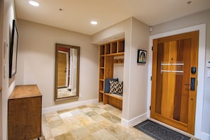 A hallway with a wooden door, a mirror, and a shelf with a cushion. - Pinnacle Ridge 36 - Ski in Ski out, Private Hot Tub, Wood Fireplace (Whistler)