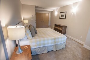 A bedroom with a bed, bedside table, lamp, dresser, and a door leading to another room. - Pinnacle Ridge 36 - Ski in Ski out, Private Hot Tub, Wood Fireplace (Whistler)
