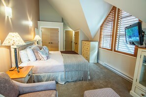 A bedroom with a bed, bedside tables, a TV, and a window with blinds. - Pinnacle Ridge 36 - Ski in Ski out, Private Hot Tub, Wood Fireplace (Whistler)