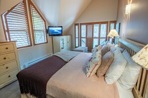 A bedroom with a large bed, a television, and multiple windows with blinds. - Pinnacle Ridge 36 - Ski in Ski out, Private Hot Tub, Wood Fireplace (Whistler)