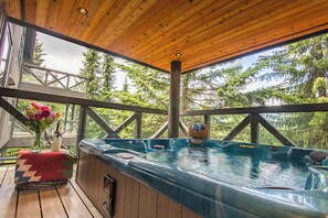 A wooden deck with a hot tub, a wicker basket, and a vase with flowers. - Pinnacle Ridge 36 - Ski in Ski out, Private Hot Tub, Wood Fireplace (Whistler)