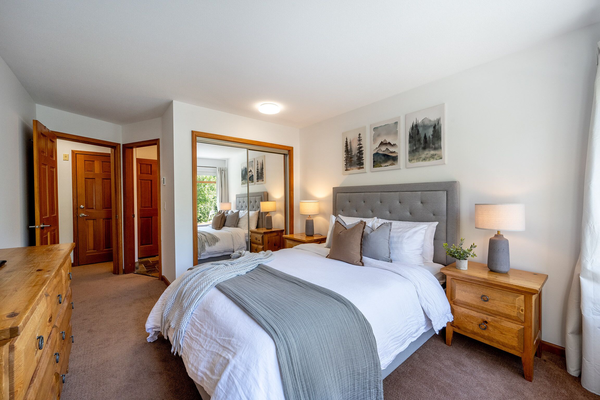 Une chambre à coucher avec un grand lit, une commode en bois et une table de chevet avec une lampe.