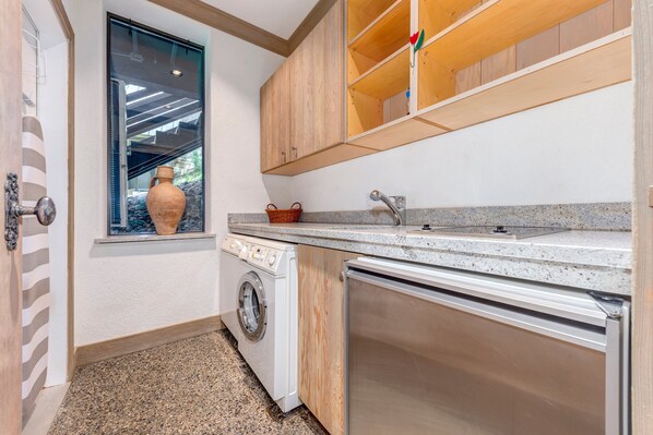 A compact kitchen with a washing machine, a sink, and wooden cabinets.