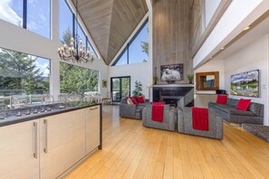A spacious living area with a kitchen island, large windows, and a fireplace.