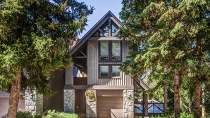 A modern log cabin with a stone facade, large windows, and a garage. - Pinnacle Ridge 5 - Ski in Ski out, Private Hot Tub, Gas Fireplace (Whistler)