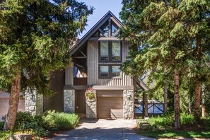 A cabin with a stone foundation, wooden exterior, and a large garage door.