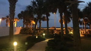 A pathway lined with palm trees and illuminated by street lamps, leading towards a building with a view of the sea. - Fall is coming! Book! Unit #1309 @ Seaside Beach & Racquet Club ~Prime~Location~ (Orange Beach)