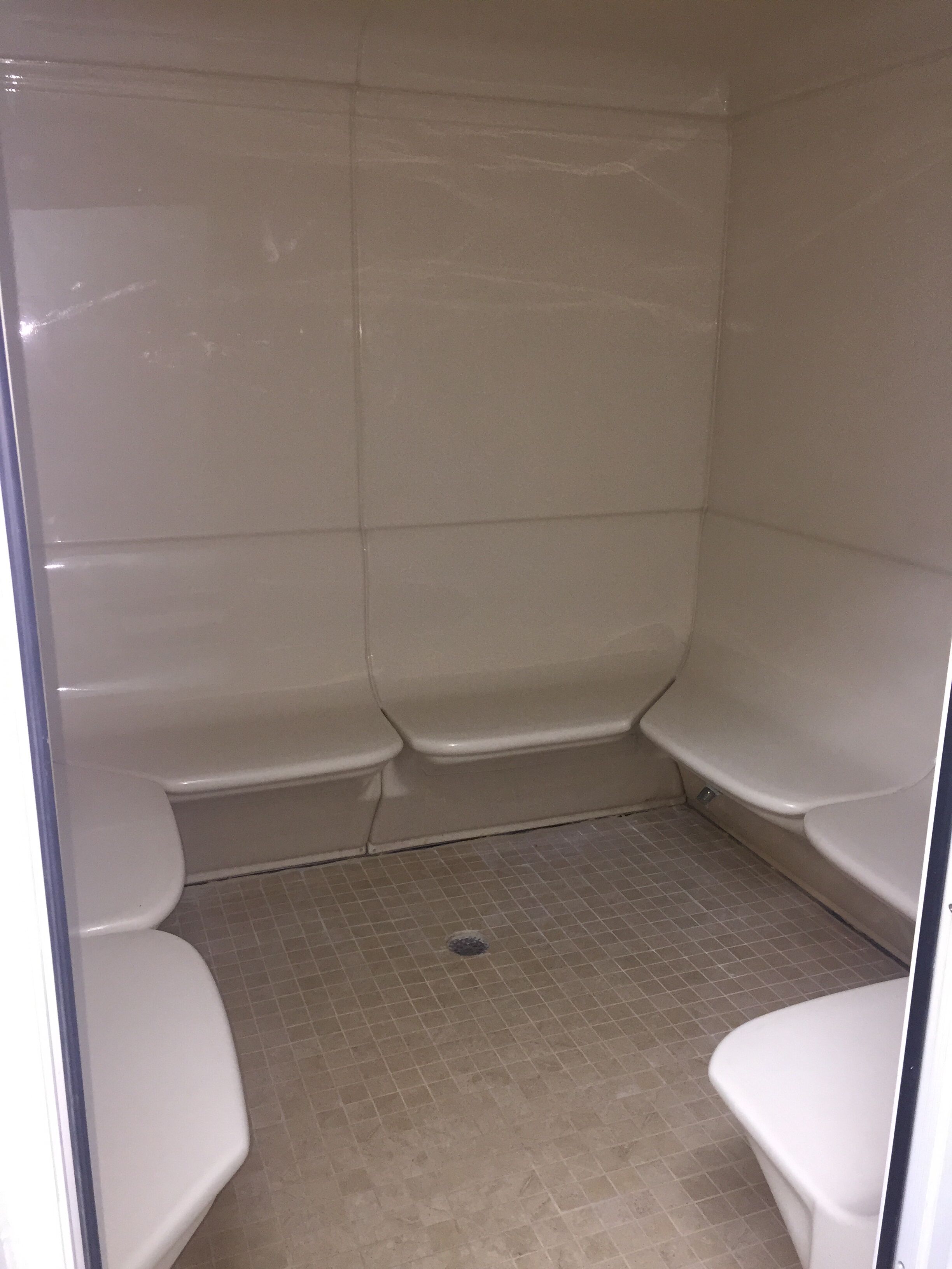 Un baño pequeño con azulejos, zona de ducha y dos inodoros.