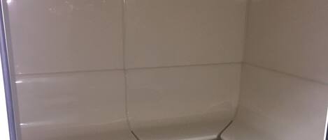 Un baño pequeño con azulejos, zona de ducha y dos inodoros.
