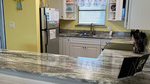 A kitchen with a marble countertop, white cabinets, and a window with a beach-themed curtain. - Fall is coming! Book! Unit #1309 @ Seaside Beach & Racquet Club ~Prime~Location~ (Orange Beach)