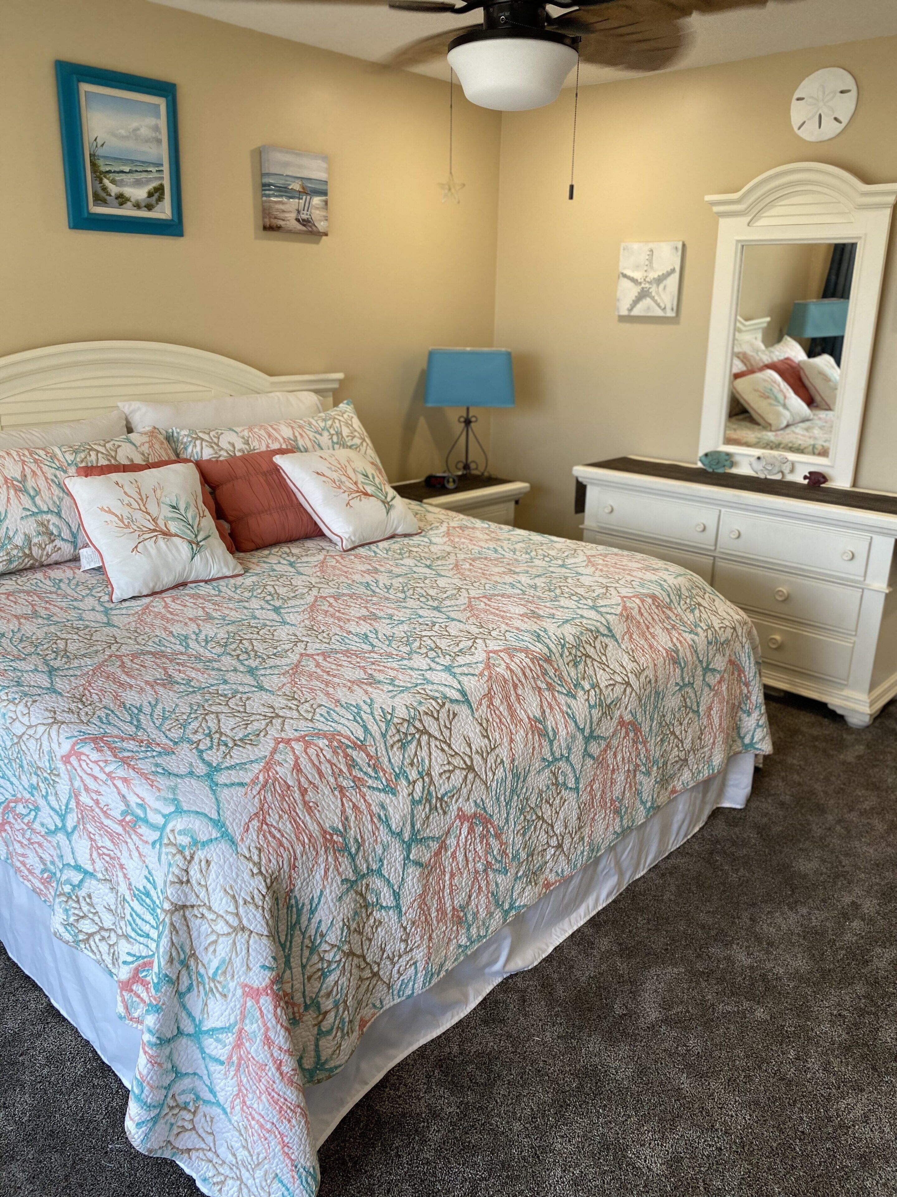 A bedroom with a bed, nightstand, dresser, and a ceiling fan.
