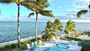 A poolside area with lounge chairs, a small hot tub, and a view of the ocean. - Oceanfront Home on Deep Water Canal w/Dock, Pool, Hot Tub, Kayaks, Pool Table! (Marathon)