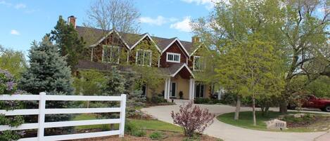 A two-story house with a front porch, a driveway, and a white picket fence.