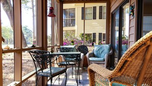 A covered patio with wicker furniture, a table, and chairs. - Penny-Wise Paradise In Pawleys Island (Pawleys Island)