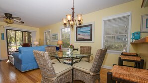 A dining area with wicker chairs, a glass table, and a ceiling fan. - Penny-Wise Paradise In Pawleys Island (Pawleys Island)