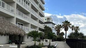 Un hôtel à plusieurs étages doté de balcons, d’une cour dallée et de palmiers.