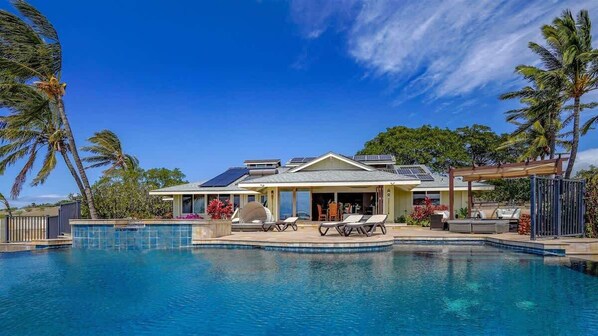 Ein Resort mit Swimmingpool, Liegestühlen und einer überdachten Terrasse.