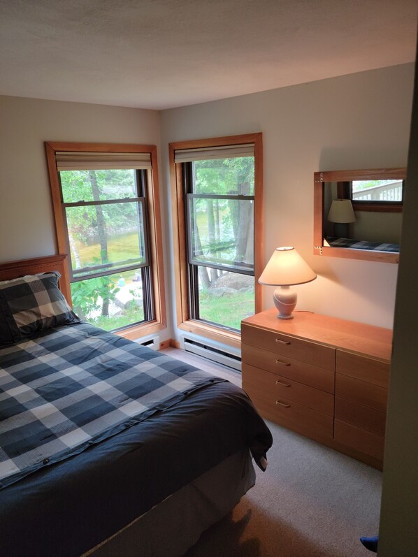 A bedroom with a bed, a dresser, a lamp, and two windows with a view of trees. - Riverfront, Vacation! Spacious, Bright, Clean! 3 Br/2 Ba
WEEKEND SHUTTLE TO LOON (Lincoln)