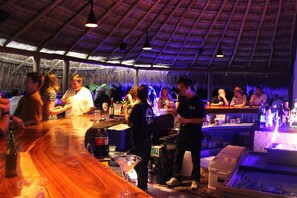 A bar area with wooden counters and a thatched roof.