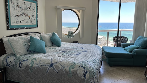 Une chambre avec un lit, une vue sur l’océan, un balcon et une chaise.