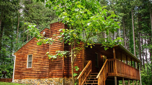 A wooden cabin with a porch and a staircase, surrounded by trees. - Mountaineer Cabin 6 - Hot Tub & Gas Fireplace close to New River Gorge (Hico)