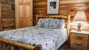 A wooden-paneled room with a bed, a nightstand, and a framed picture on the wall. - Mountaineer Cabin 6 - Hot Tub & Gas Fireplace close to New River Gorge (Hico)