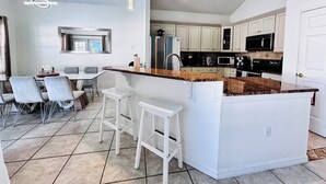 A modern kitchen with white cabinets, a granite countertop, and a central island with bar stools.