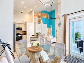 A modern kitchen with white cabinets, a built-in oven, and a dining area with a glass table and chairs. - 10 minutes to Disney! Two Pools & Spa! No Carpet! Themed Rooms @The Nemo House (Kissimmee)