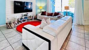 A modern living room with a white sofa, a red rug, and a ceiling fan.
