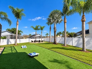A backyard with artificial grass, a badminton net, and palm trees. - 10 minutes to Disney! Two Pools & Spa! No Carpet! Themed Rooms @The Nemo House (Kissimmee)