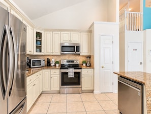 A kitchen with white cabinetry, stainless steel appliances, and a tiled floor. - 10 minutes to Disney! Two Pools & Spa! No Carpet! Themed Rooms @The Nemo House (Kissimmee)