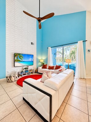 A modern living room with a white sofa, a red rug, and a ceiling fan. - 10 minutes to Disney! Two Pools & Spa! No Carpet! Themed Rooms @The Nemo House (Kissimmee)