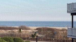 A coastal view with a beach, a wooden fence, and a lamp post.