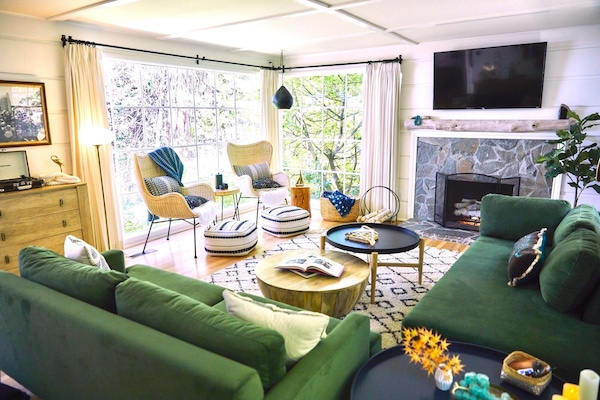 Light filled living room with walls of windows that look into the forest