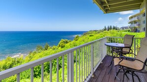 A balcony with a view of the ocean, a table, and two chairs. - Gorgeous Ocean Views From All Rooms! Corner Unit! Cool AC! Aloha Galore! (Princeville)