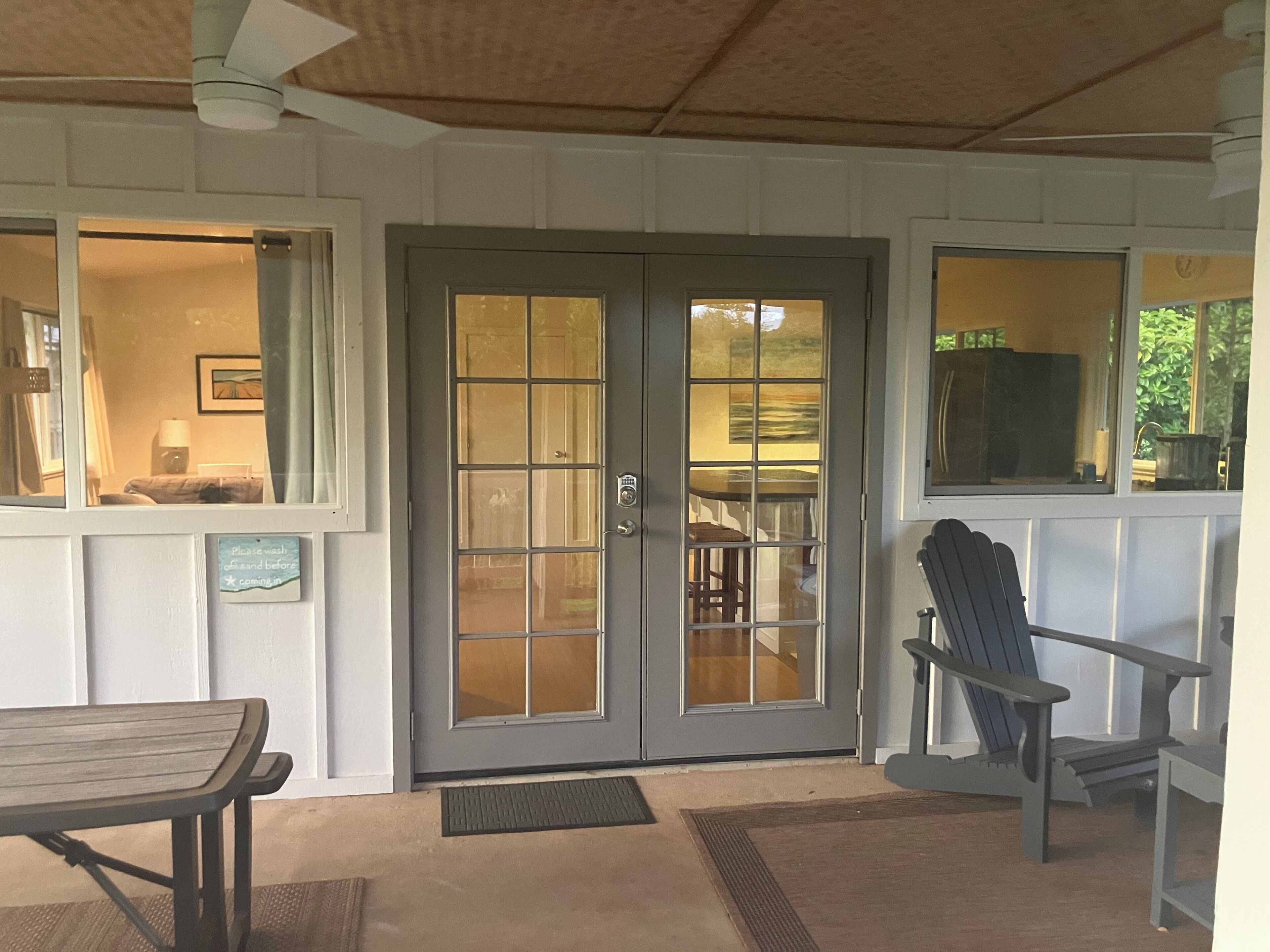 A covered porch with a bench, a chair, and a door with frosted glass panels.
