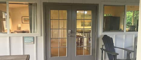 A covered porch with a bench, a chair, and a door with frosted glass panels.