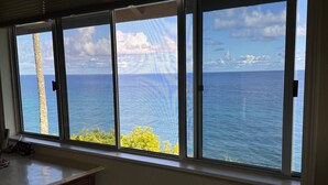 Una habitación con un ventanal grande con vistas al mar, una mesa de madera y una silla.