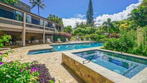Un hotel moderno con piscina, zona de estar al aire libre y abundante vegetación.