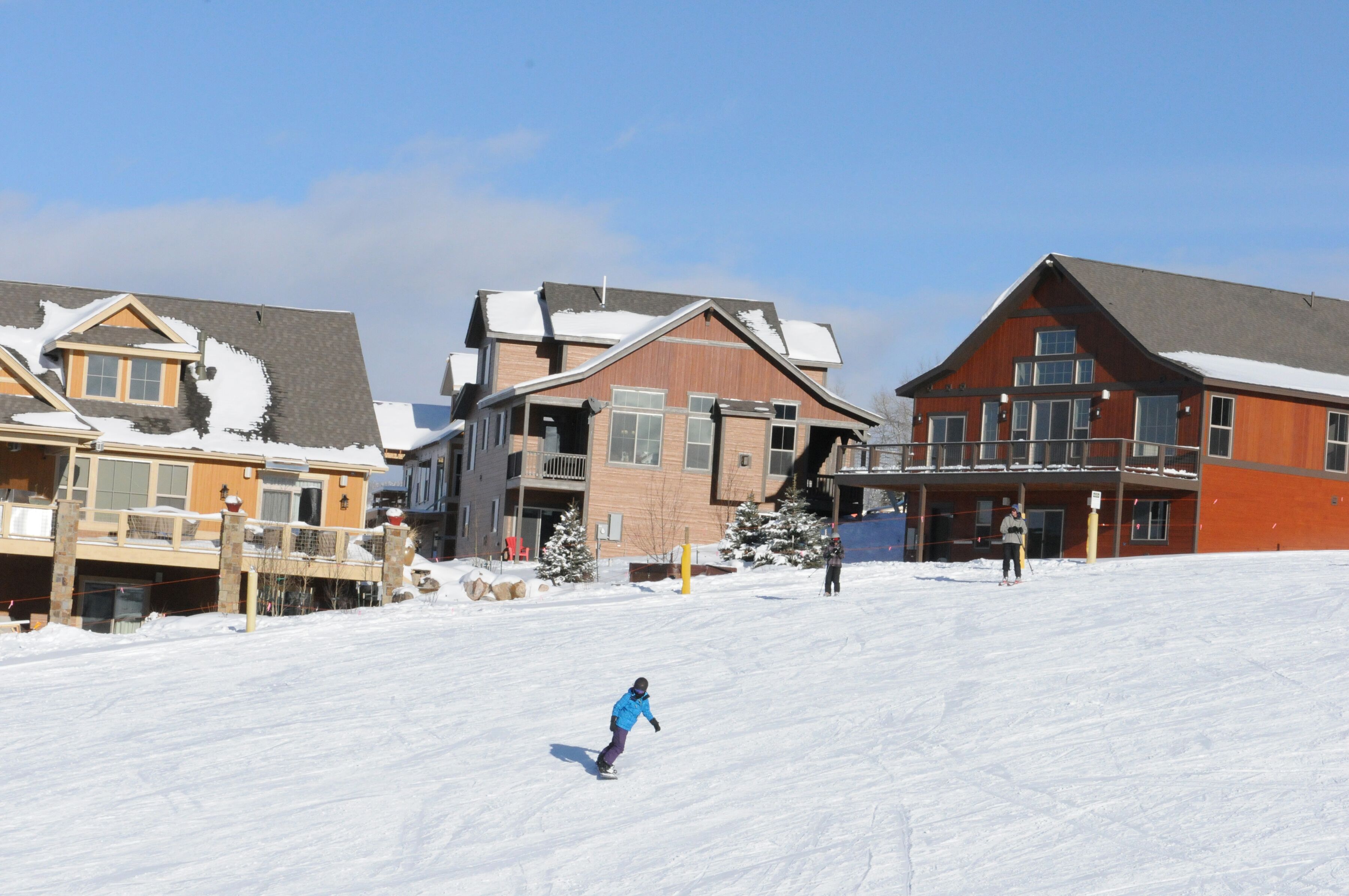 A snow-covered ski slope with a person snowboarding.