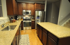A kitchen with wooden cabinets, stainless steel appliances, granite countertops, and a patterned rug. - Beautiful 5 bedroom + sleeping loft ski-in/ski-out Mountain House (Granby)